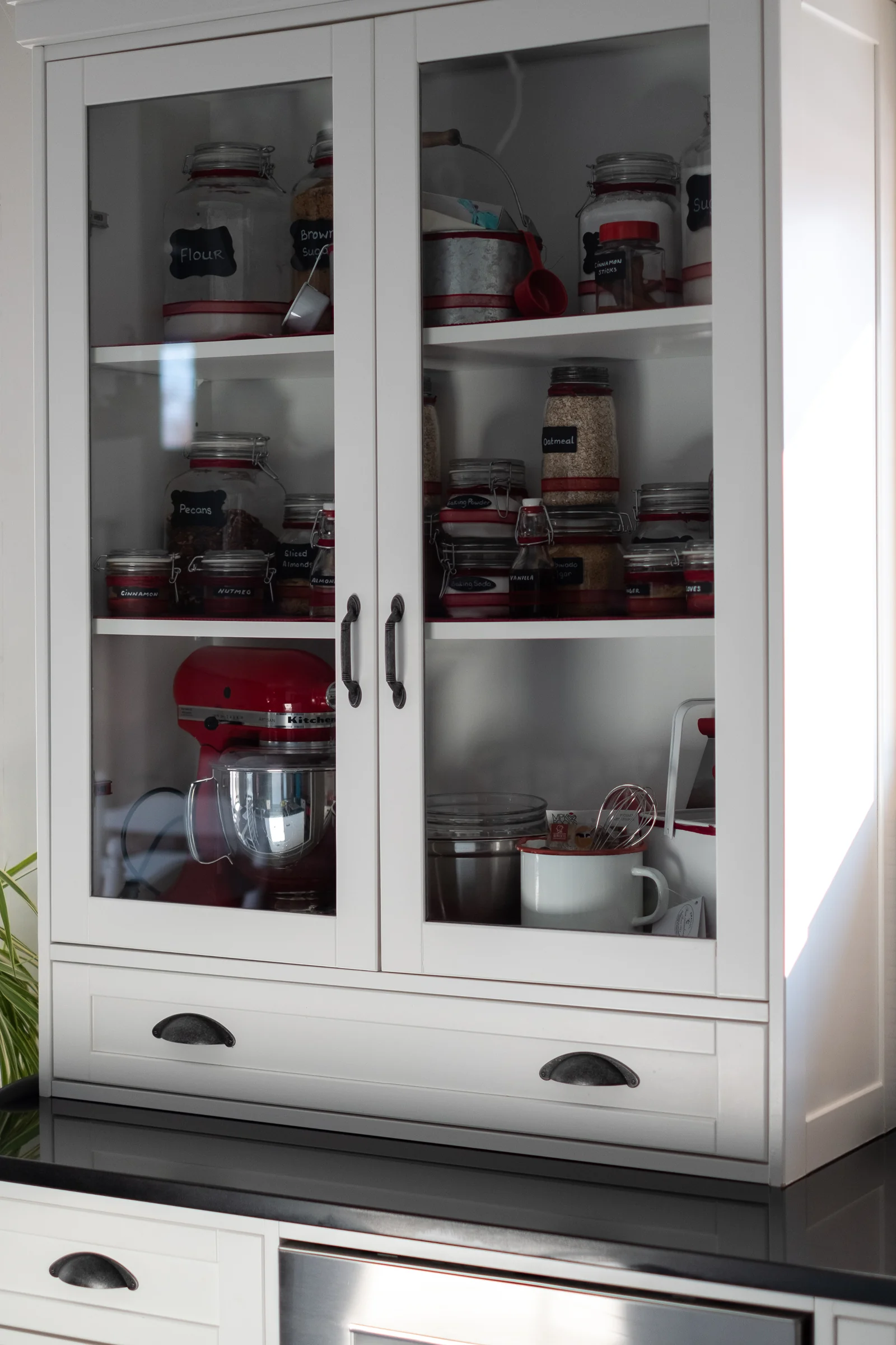 Glass-front cabinetry displaying baking essentials and KitchenAid mixer
