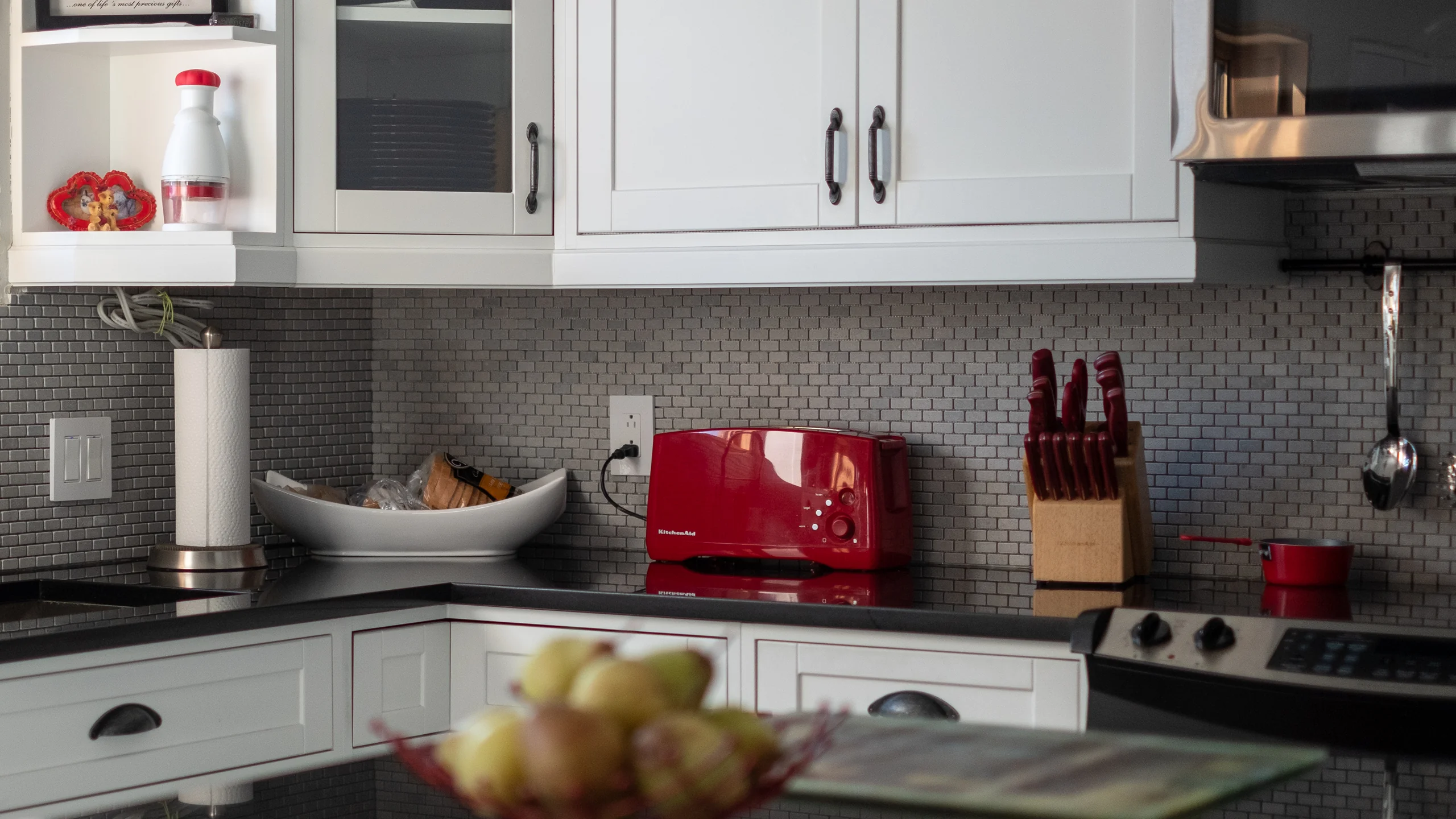 Prep area with red accent appliances and metallic backsplash
