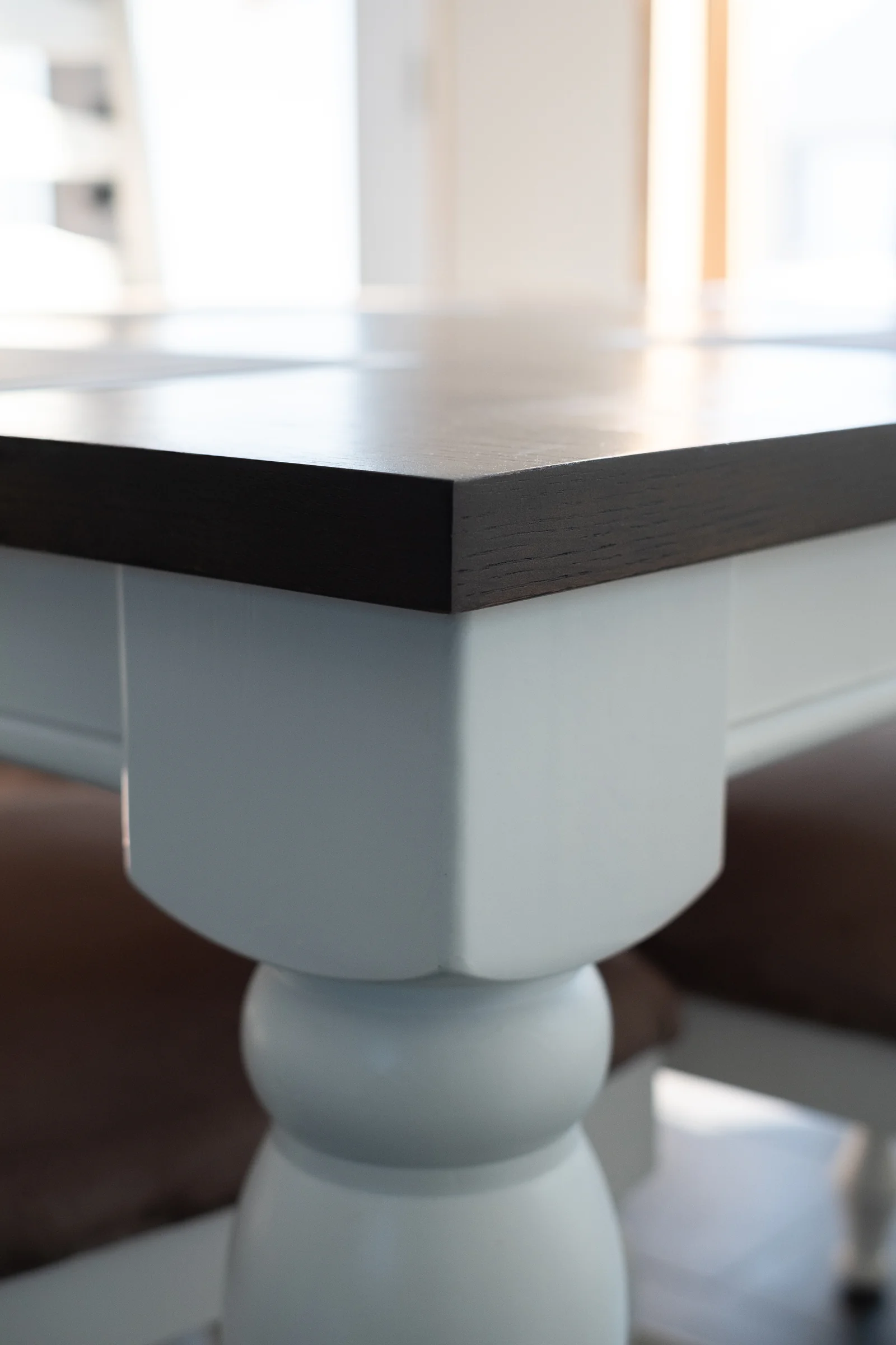 Detail of dark wood dining table with white turned leg