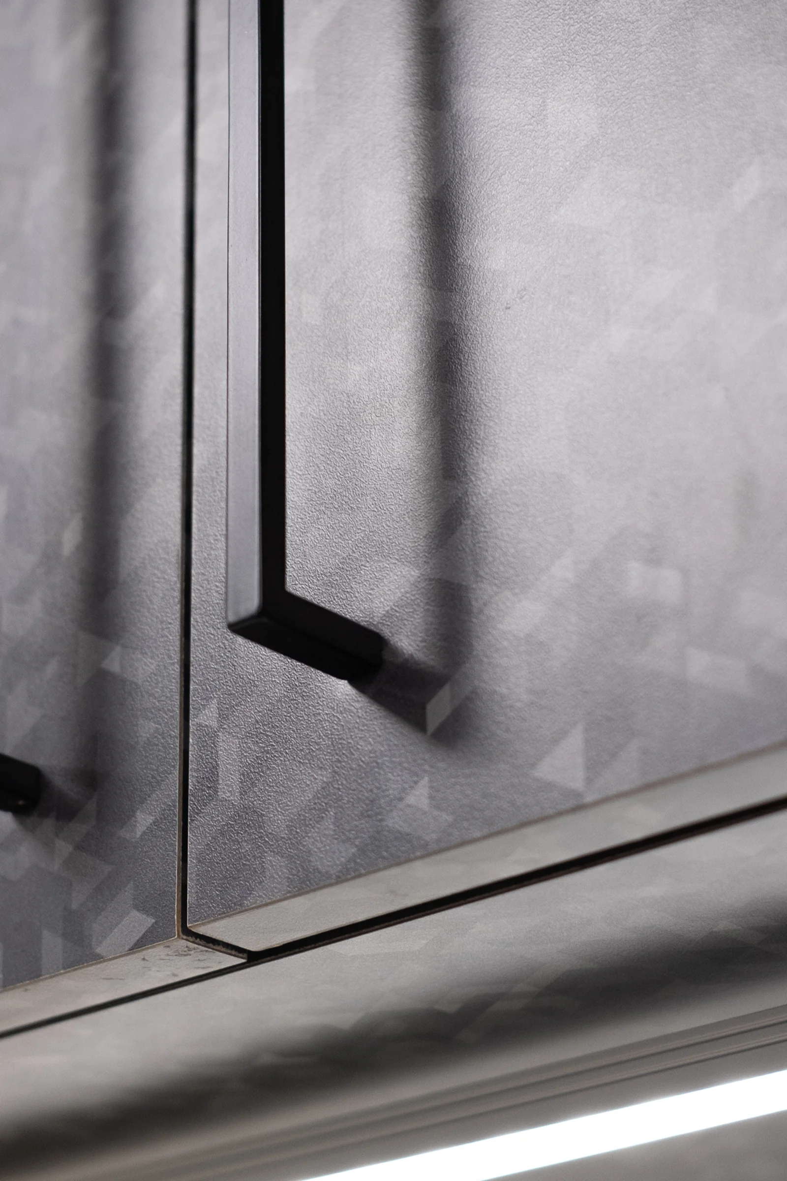 Dark grey cabinetry with geometric patterning and minimalist black bar handles