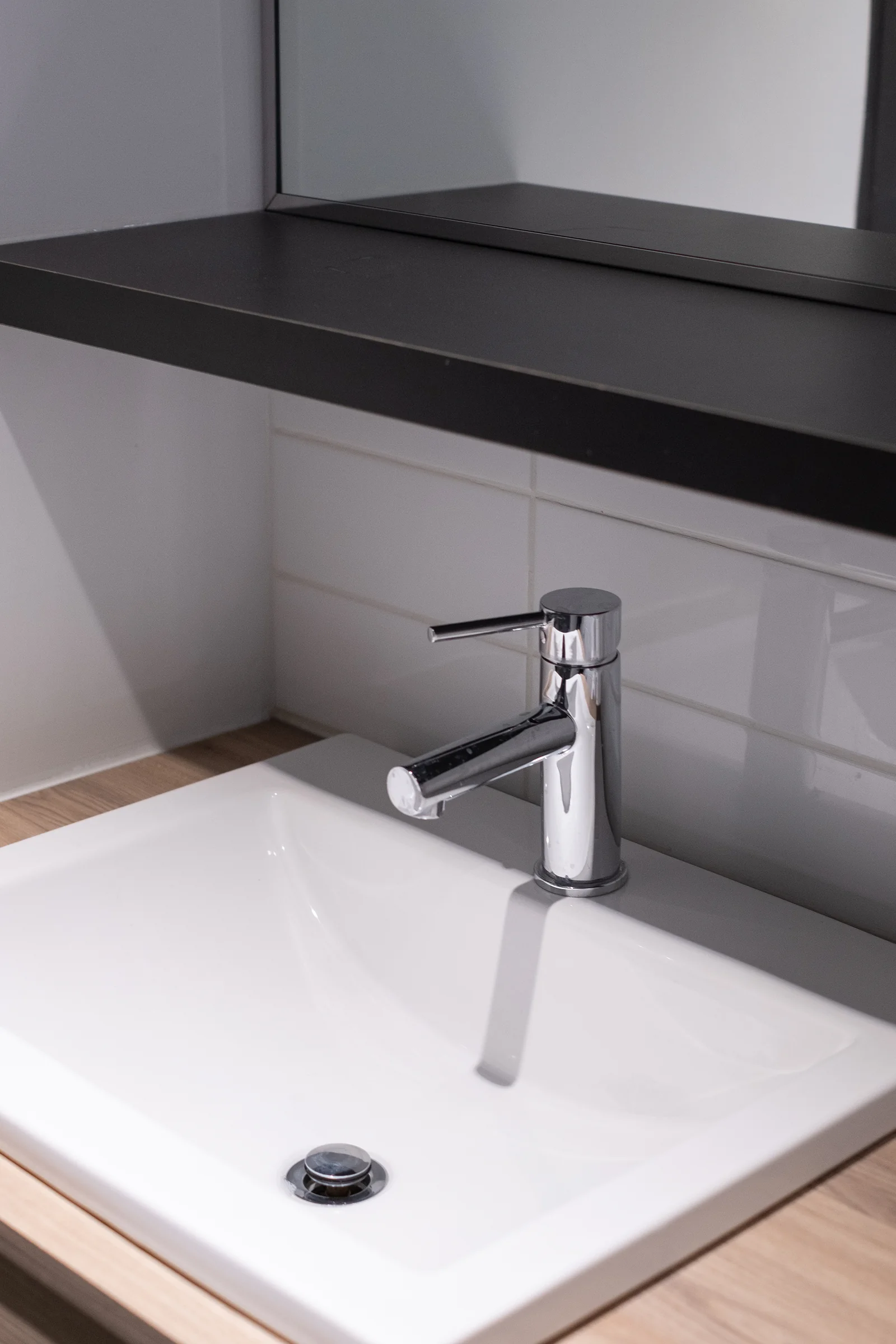 Bathroom vanity with wood-grain countertop and dark floating shelf