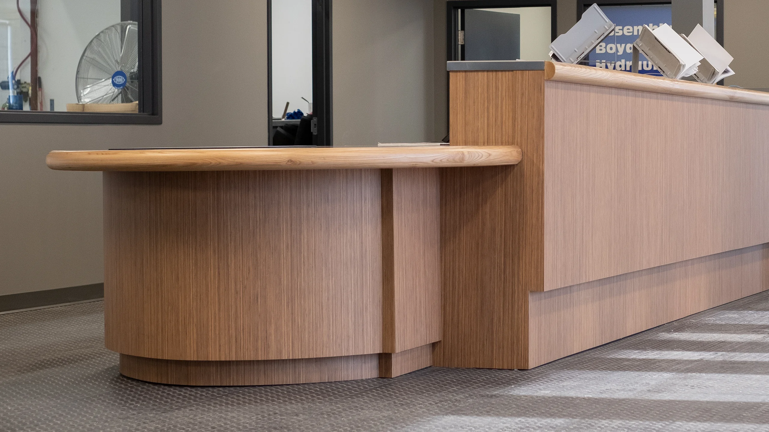 Curved wood-grain reception desk with Green Line samples