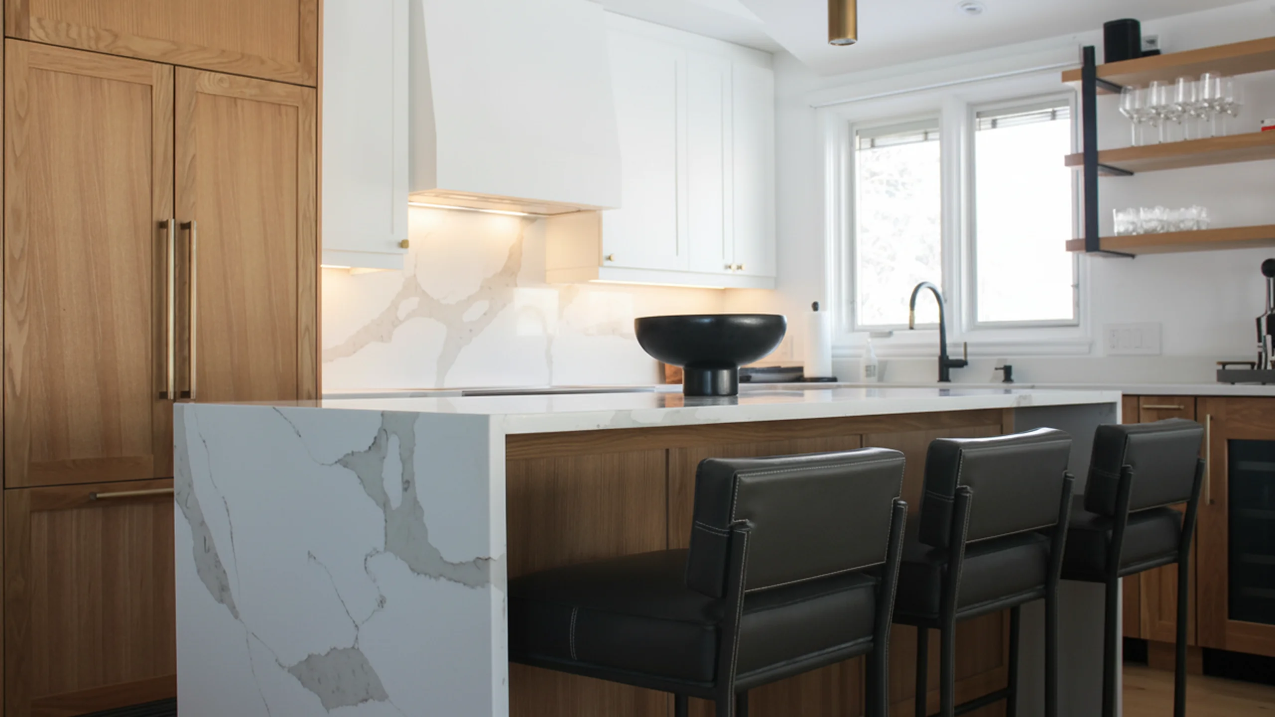 Contemporary kitchen with marble countertops, integrated backsplash and waterfall island