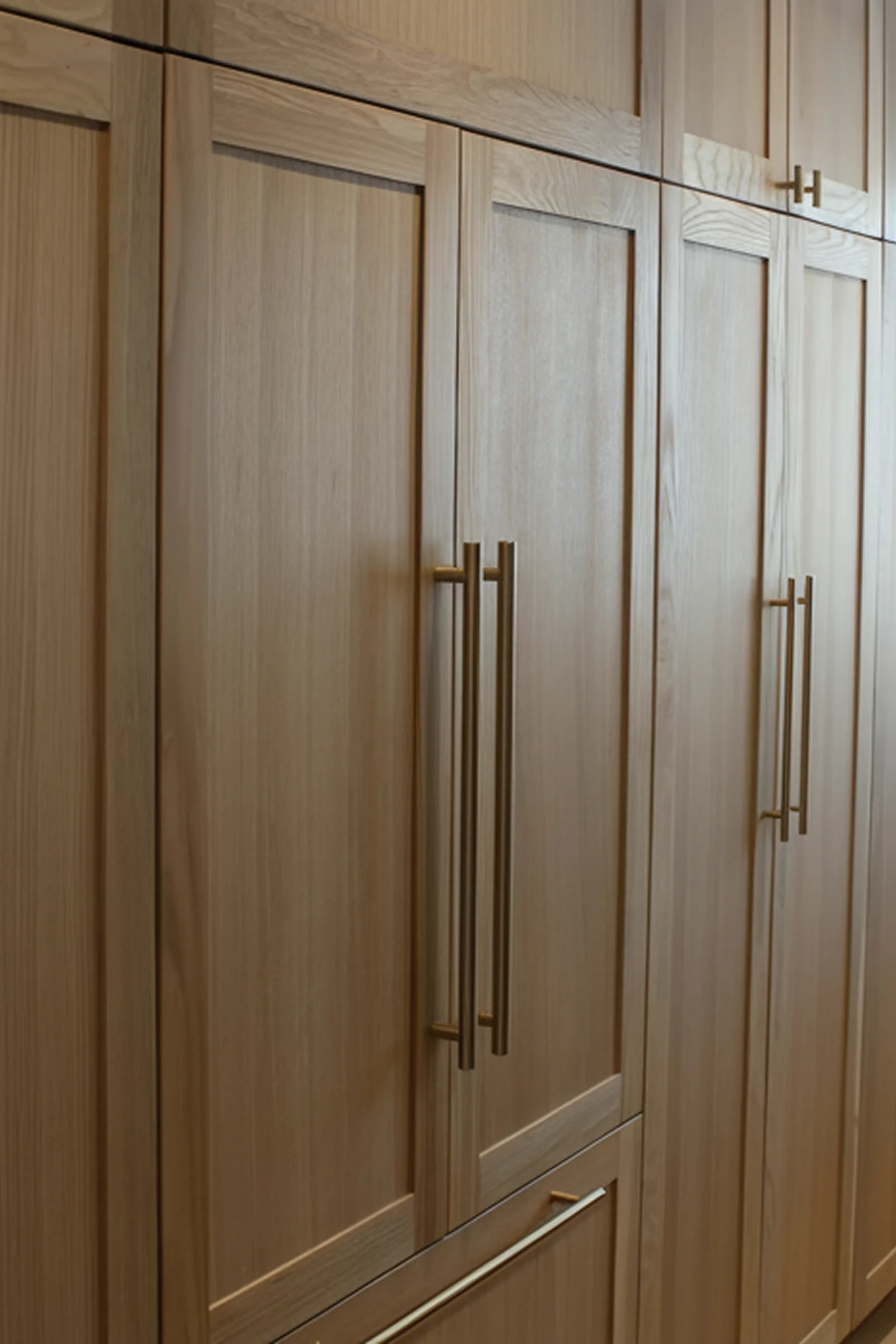 Shaker-style wood cabinetry with brass bar pulls